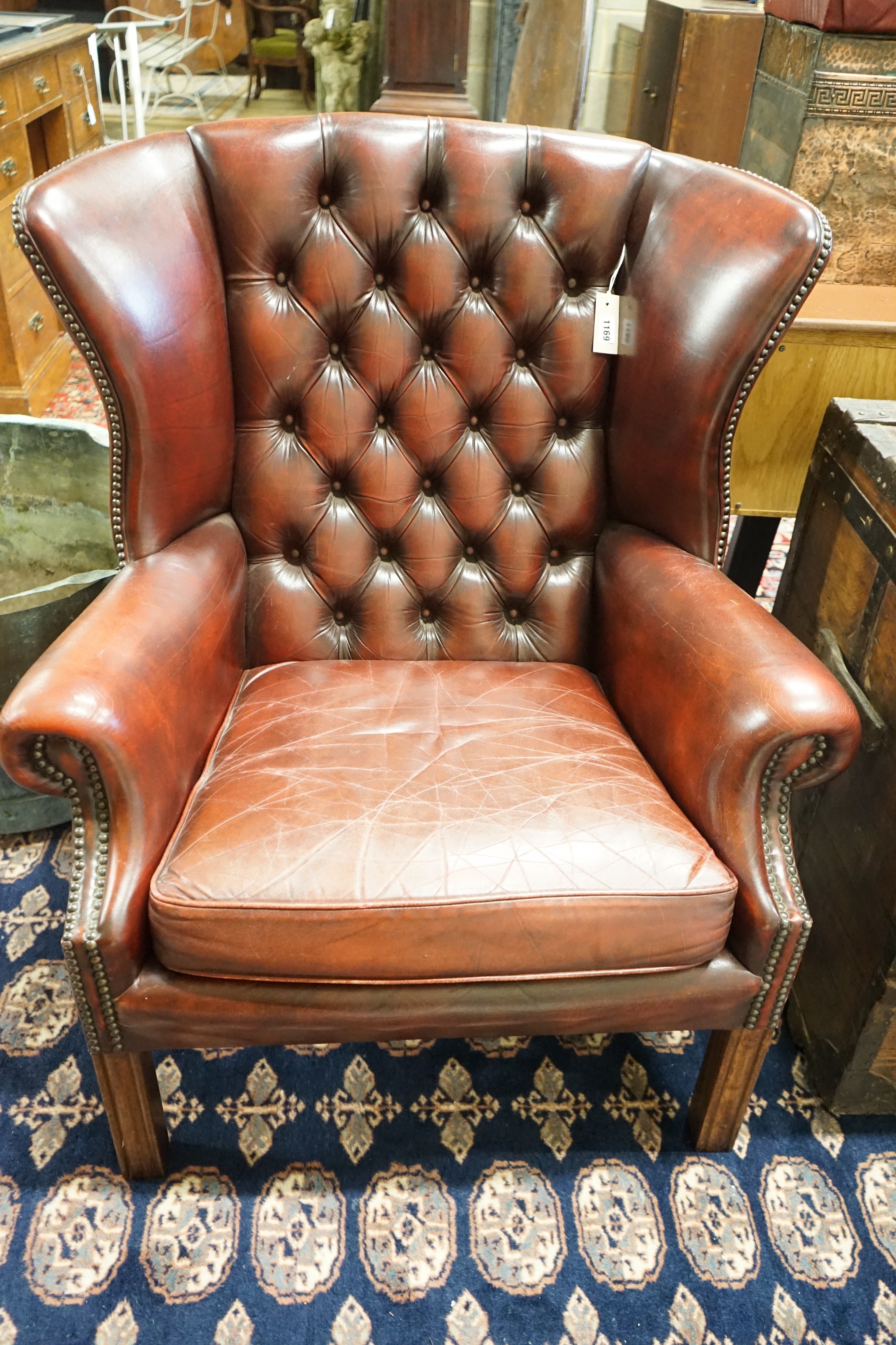 A George III style button back burgundy leather wing armchair, width 83cm, depth 66cm, height 82cm